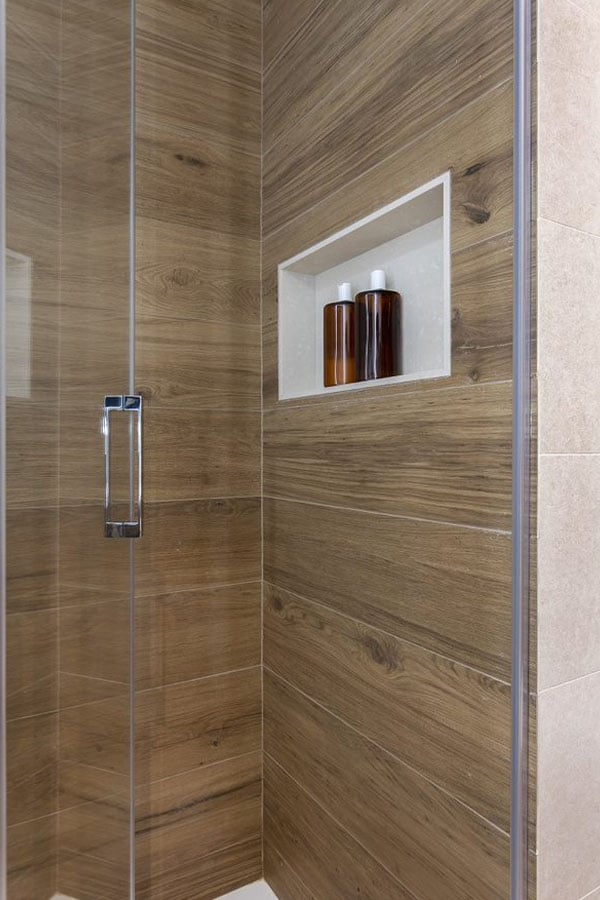 Detalle del interior de la ducha con panelado de madera y espacio para botes