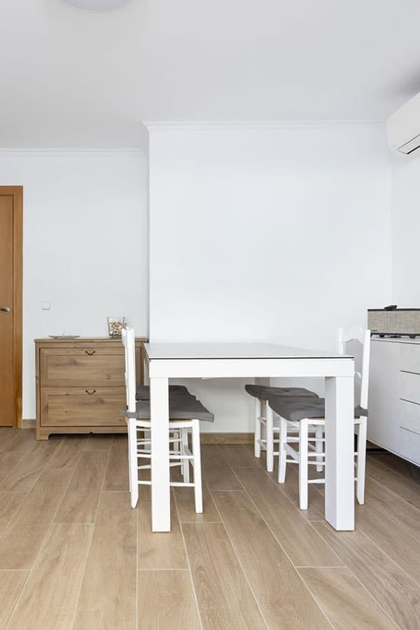 Mesa de comedor con sillas blancas y pequeña cómoda al fondo