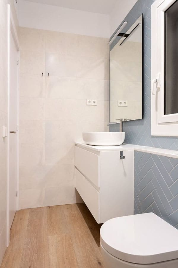 Vista lateral de un baño con pared en azul y mobiliario blanco