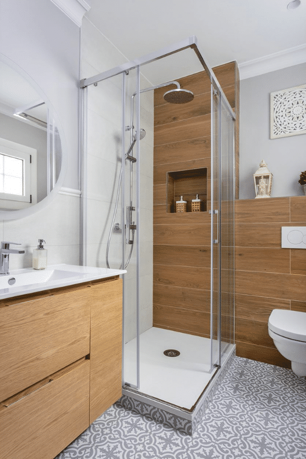 Baño con ducha con mampara esquinera y almacenamiento en madera